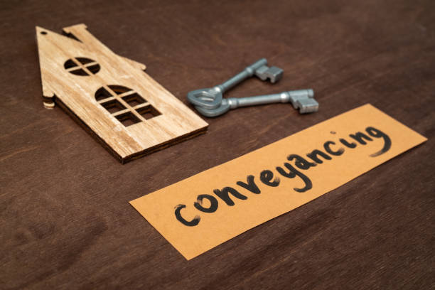 a cut out wooden house representation with a key and a card saying 'conveyancing' on wood background