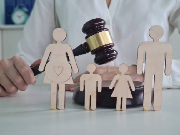A judge holds a gavel above wooden figures representing a family A judge holds a gavel above wooden figures representing a family